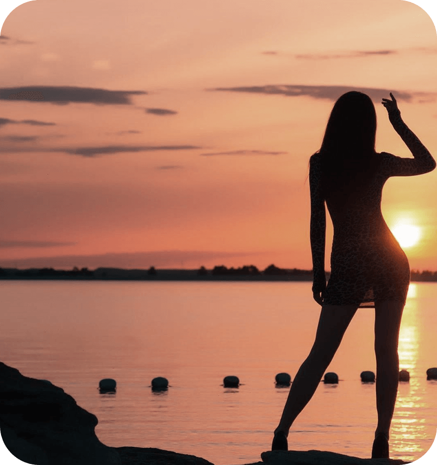 Woman standing by the water at sunset